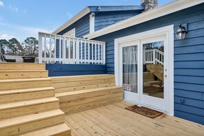 A wooden deck with a 'Welcome Home' mat, a white door with a security warning sign, and a blue exterior wall. - Unique Durham Cabin with Hot tub and close to Duke (Durham)