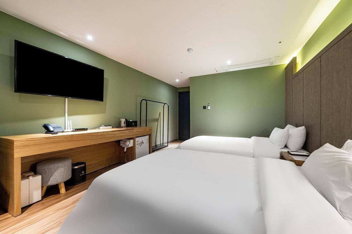 A hotel room with a large bed, a desk with a flat-screen TV, a mirror, and a wardrobe.