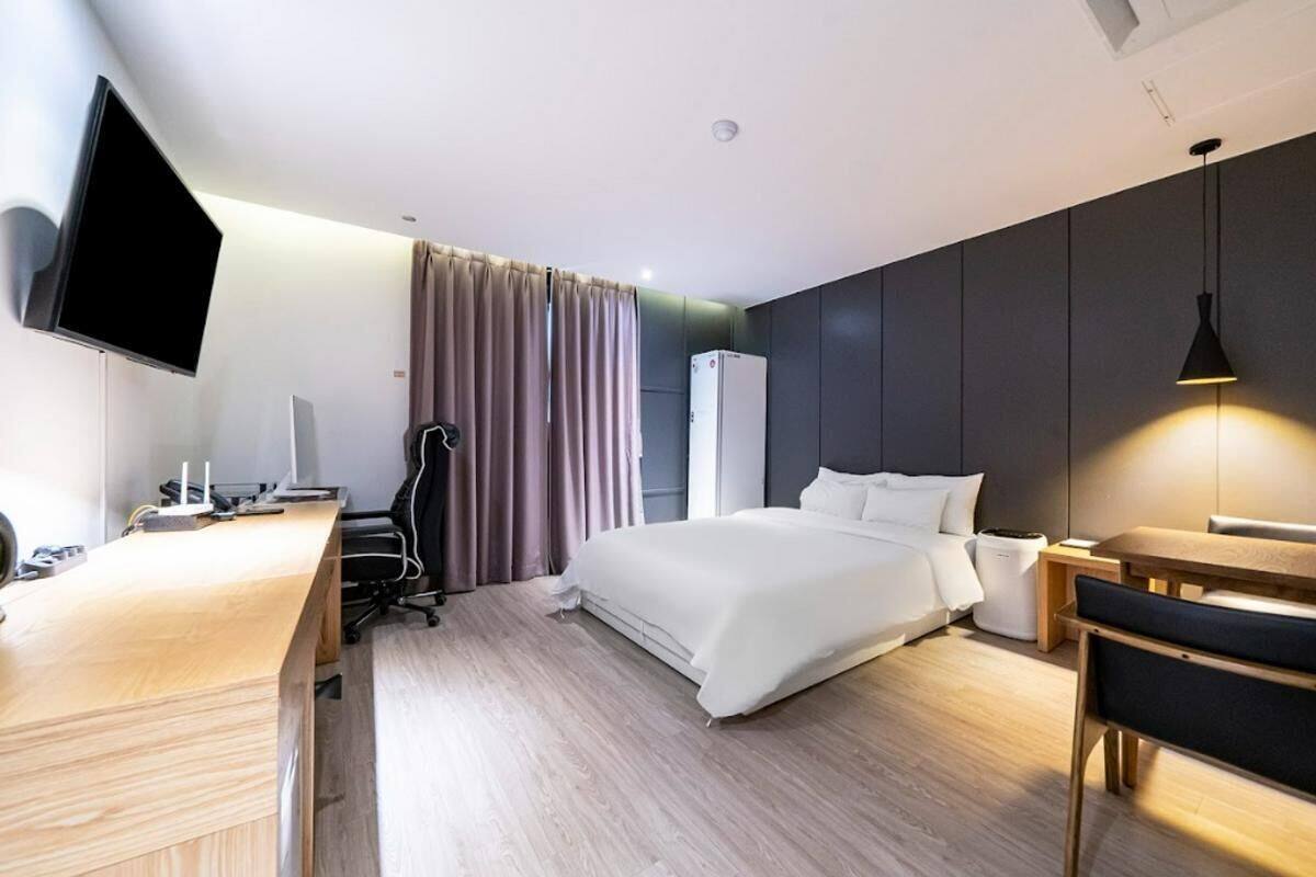 A modern hotel room with a bed, desk, flat-screen TV, and a desk lamp.