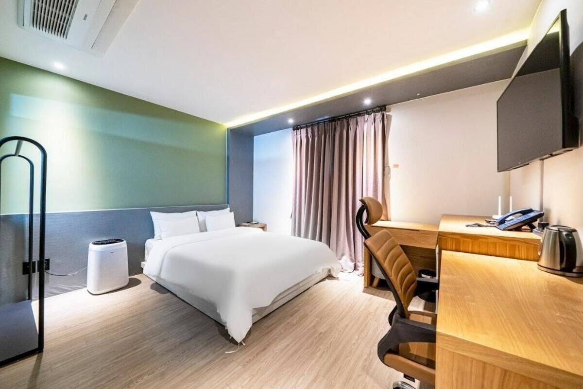 A hotel room with a bed, desk, chair, and a television.