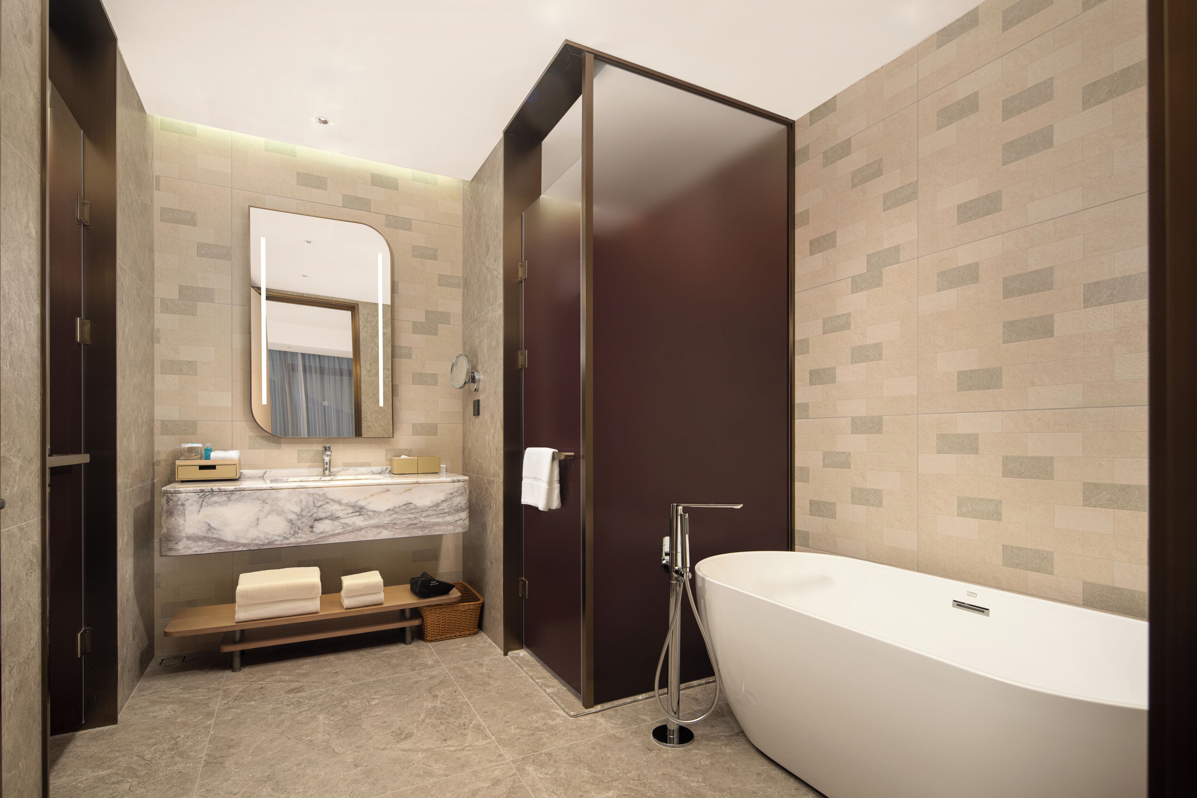 A modern bathroom with a large bathtub, a vanity with a mirror, and a shower area.