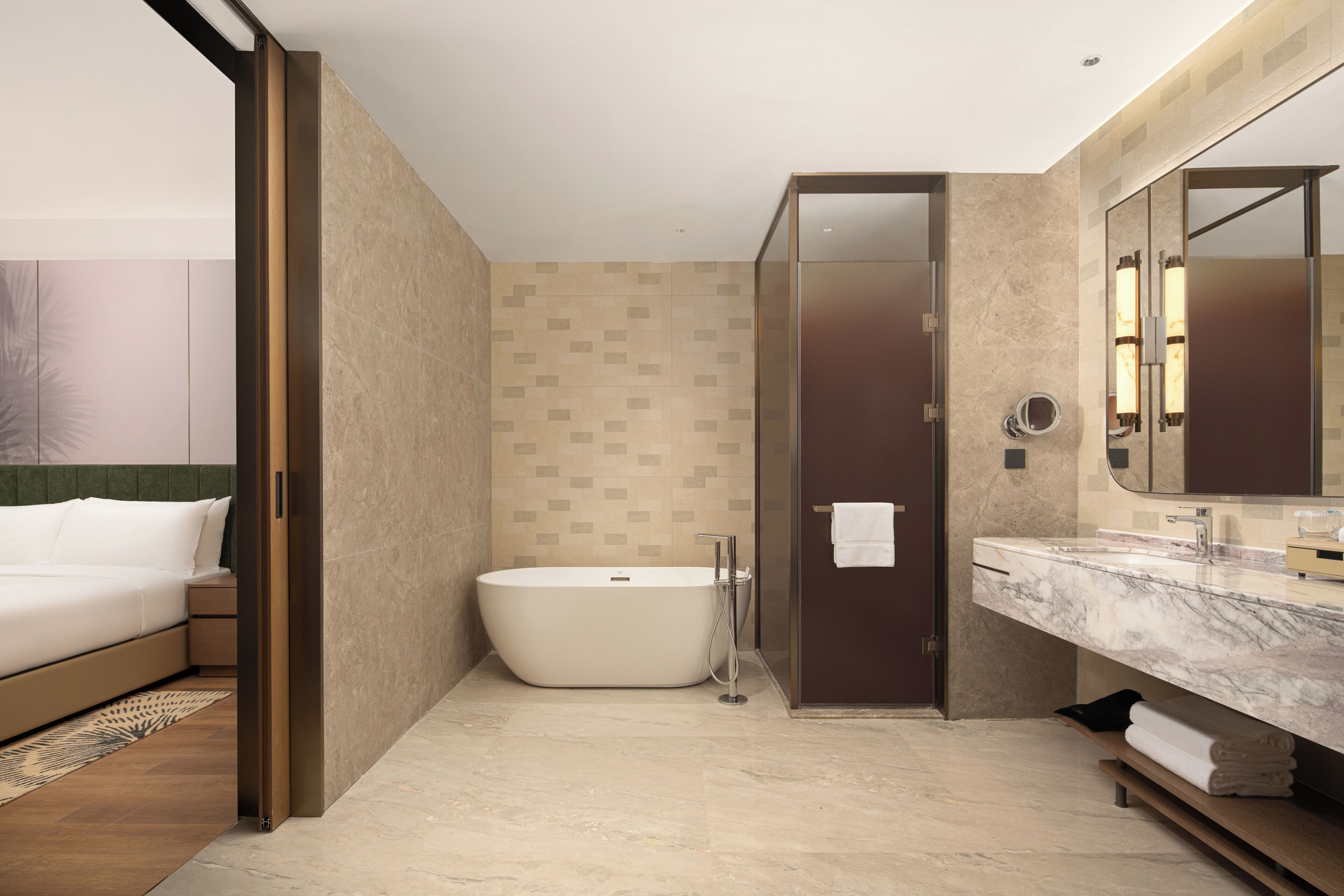 Un baño moderno con una bañera independiente, un espejo grande y una encimera de mármol.