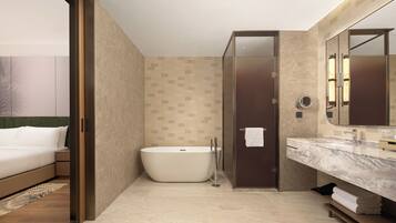 Un baño moderno con una bañera independiente, un espejo grande y una encimera de mármol.
