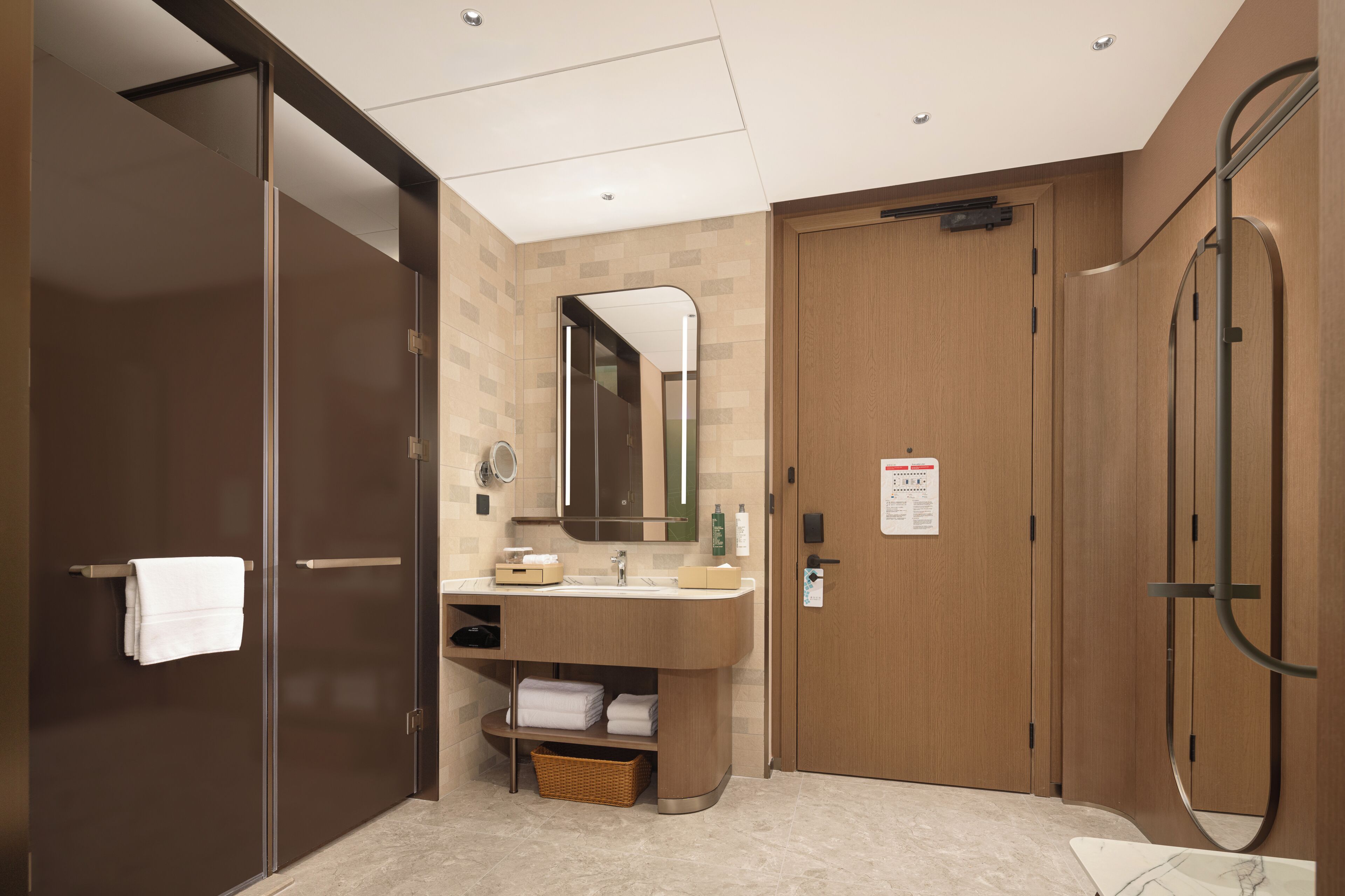 A modern bathroom with a wooden vanity, a mirror, and a shower area.