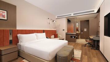 Una habitación de hotel moderna con una cama grande, un escritorio, una silla, una mesita, un banco y un espejo.