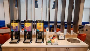 Una estación de café con tres dispensadores de café, etiquetados como 'CAFE REGULAR', 'CAFE DESCAFEINADO' y 'AGUA CALIENTE'.