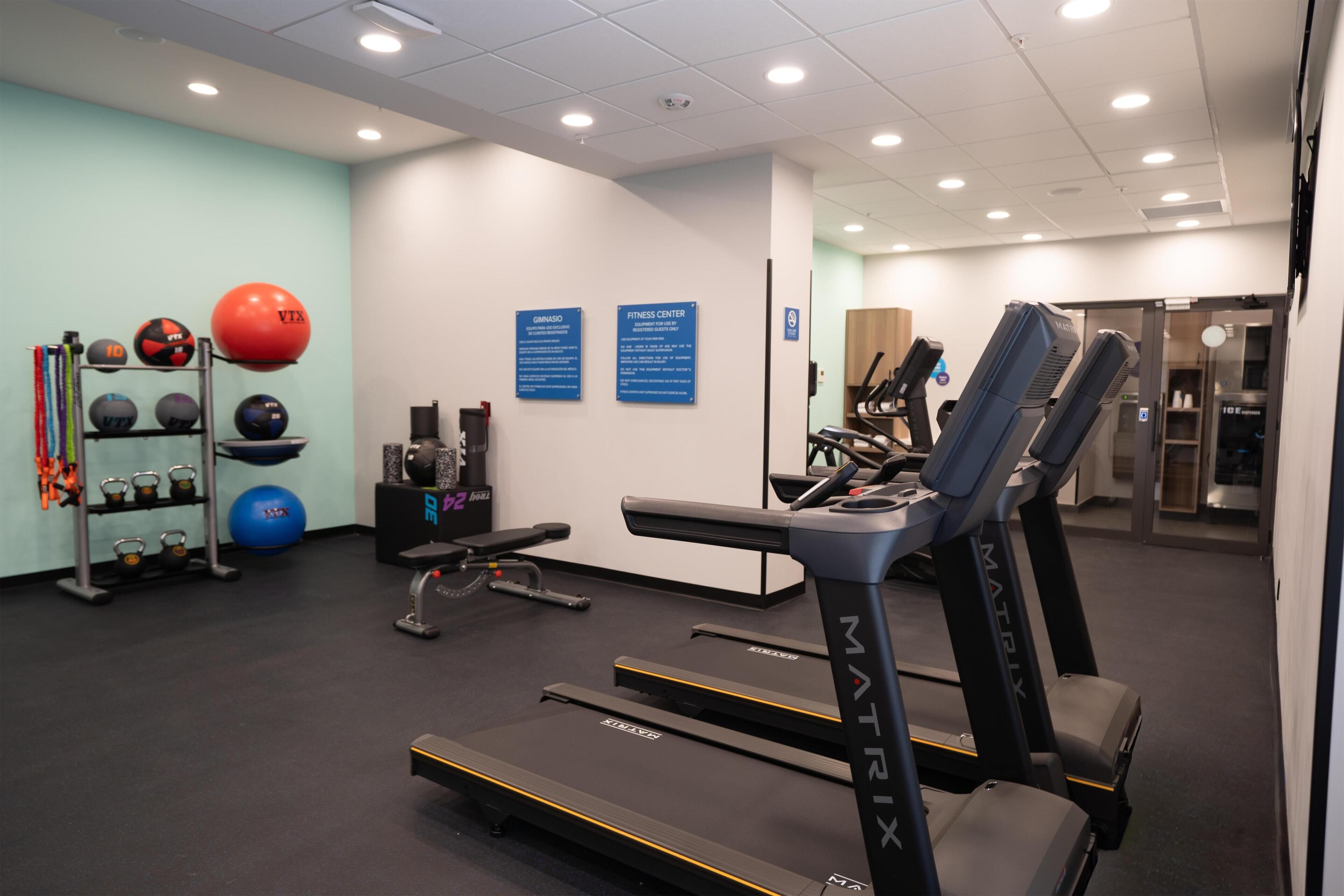 A gym with treadmills, exercise balls, and weightlifting equipment.