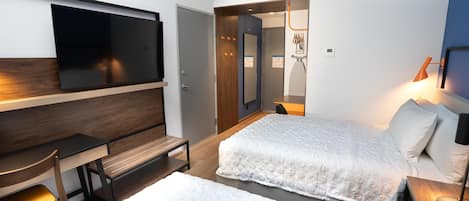 A hotel room with a bed, a desk, a chair, a television, and a lamp.