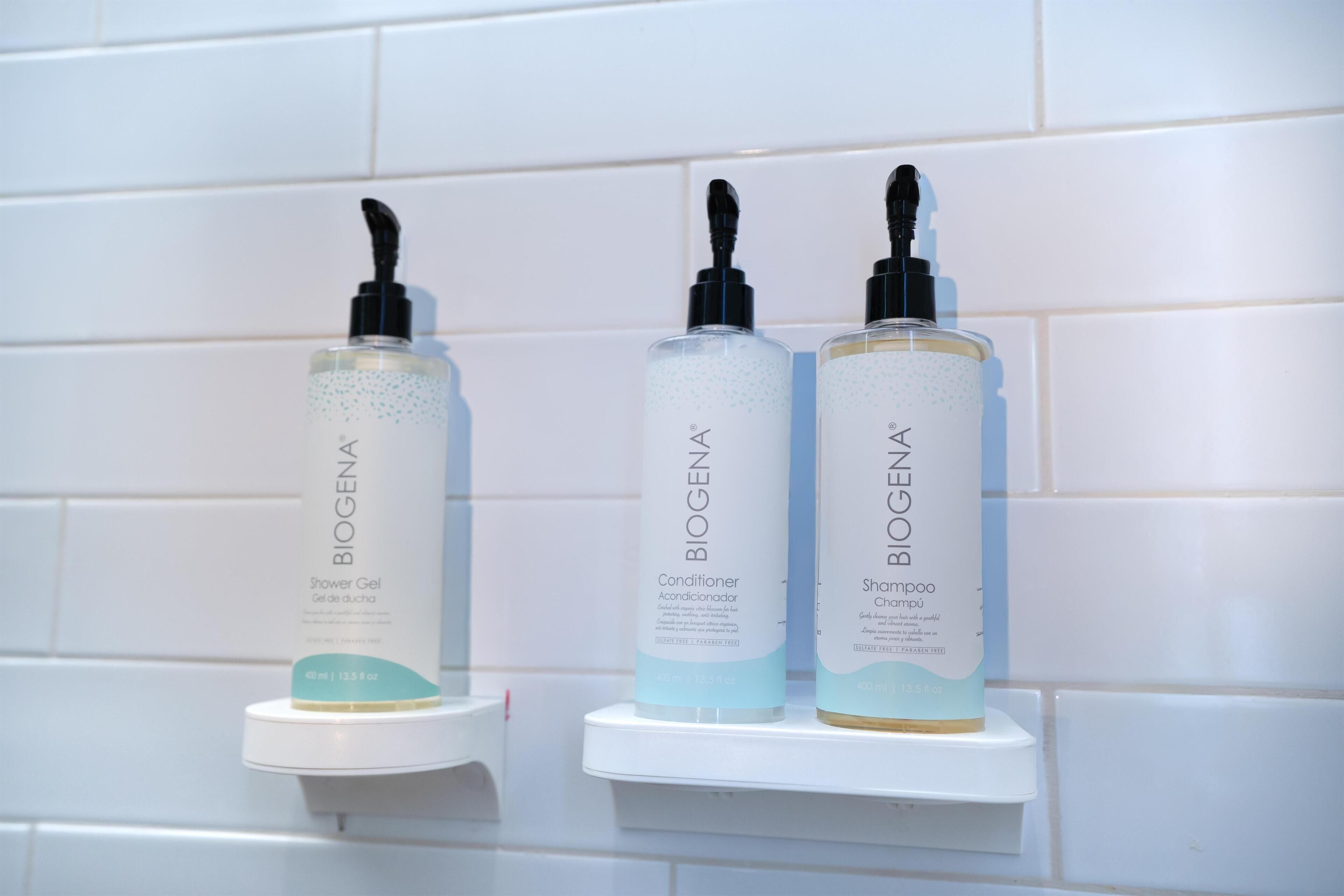 Tres productos de BiogenA sobre un estante blanco frente a una pared de azulejos blancos.