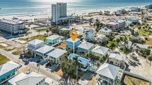 Vista aérea de un pueblo costero con un hotel destacado, frente a la playa y una combinación de edificios residenciales.