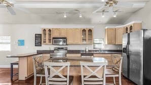 Una cocina moderna con armarios de madera, un refrigerador de acero inoxidable y una isla central con taburetes de bar.