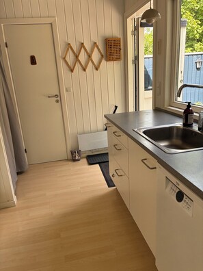 Een keuken met een spoelbak, houten vloer en een deur met een greep.
