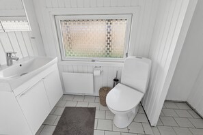 A small, white bathroom with a bathtub, toilet, and window. - Lovely cottage close to a beautiful beach (Vig)