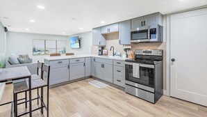 Een moderne keuken met grijze kastjes, een roestvrijstalen oven en een magnetron.