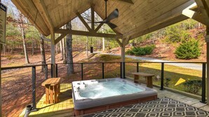 Un patio in legno con una vasca idromassaggio, una panca di legno e un tappeto decorato.