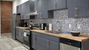 A modern kitchen with dark cabinets, a tiled backsplash, and stainless steel appliances. - Elevated Urban Living in Downtown St. Louis (St. Louis)