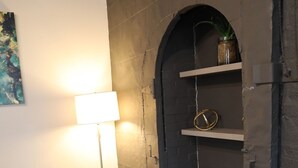 A room with two green armchairs, a floor lamp, a dark arched doorway, and a shelf with a decorative item. - Elevated Urban Living in Downtown St. Louis (St. Louis)