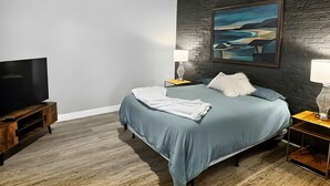 A modern bedroom with a bed, a TV, and a painting on the wall. - Elevated Urban Living in Downtown St. Louis (St. Louis)