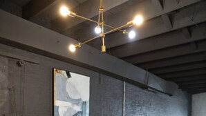 A dining area with a rectangular table, four upholstered chairs, a chandelier, and a large abstract painting on the wall. - Elevated Urban Living in Downtown St. Louis (St. Louis)
