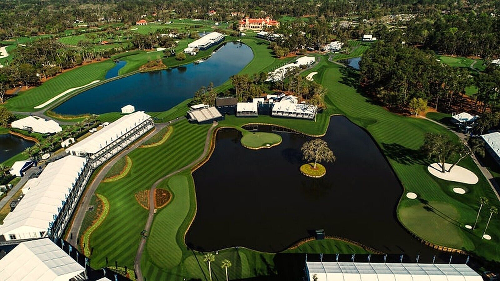 Un parcours de golf doté de plusieurs étangs, d’un club-house et entouré de verdure.