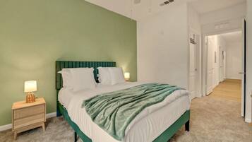 A bedroom with a bed, a bedside table, and a lamp.