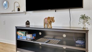 Een woonkamer met een televisietoestel waarop 'NETFLIX' staat, een beerbeeldje op een plank en een plant.