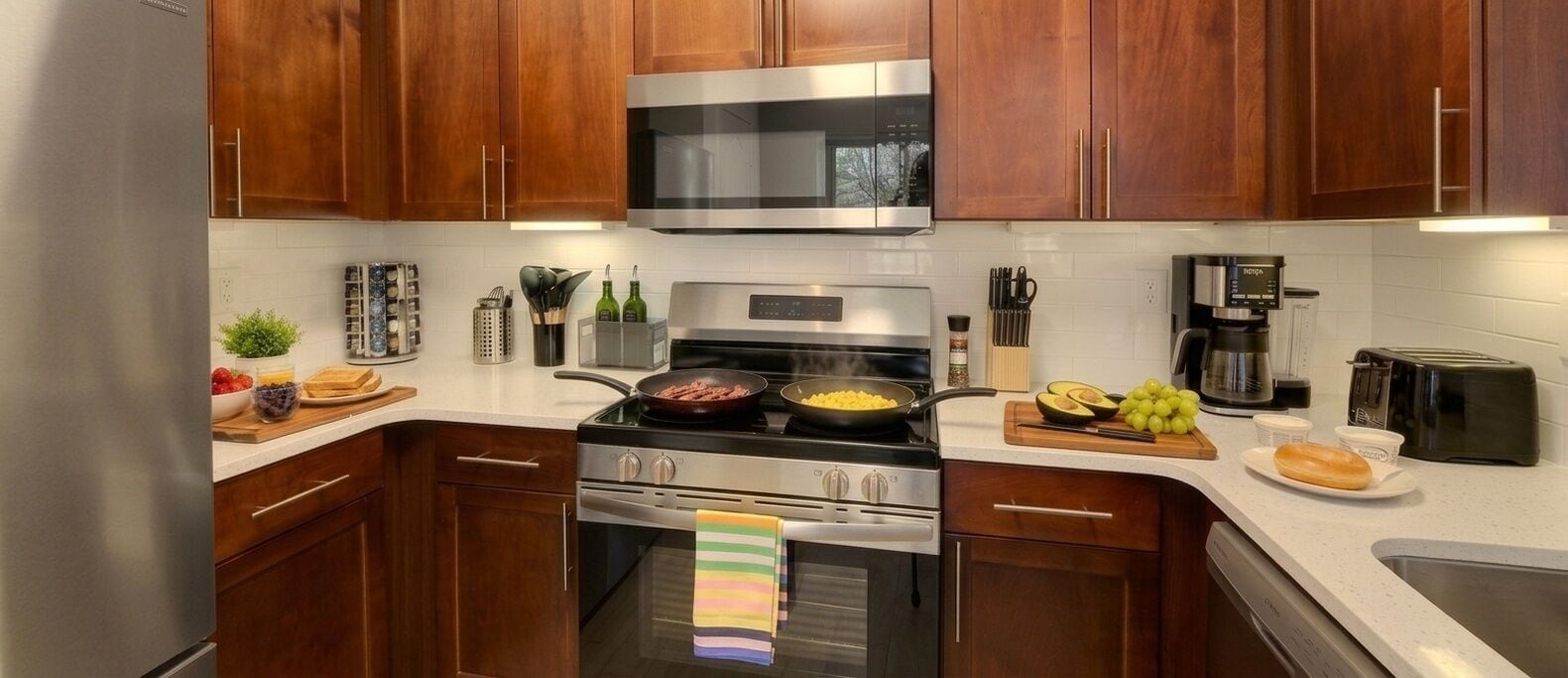 A modern kitchen with wooden cabinets, stainless steel appliances, and a variety of cooking utensils and ingredients.