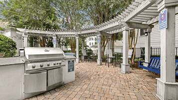 An outdoor patio with a grill, seating area, and a pergola structure.