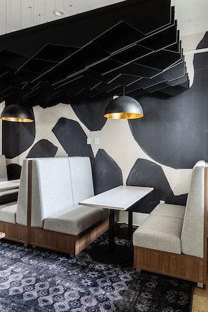 Un intérieur moderne avec un espace salon comprenant un canapé et une table, une moquette à motifs et un plafond au design géométrique.