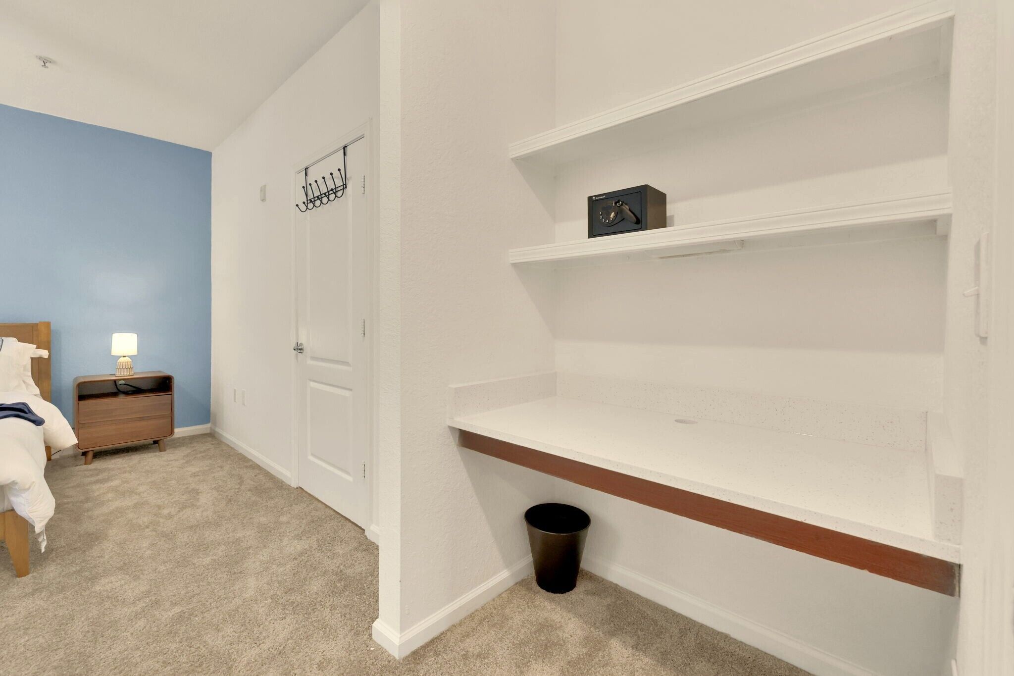 Une chambre à coucher avec un lit, une table de chevet et un mur blanc avec une porte.