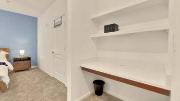 A bedroom with a bed, nightstand, and a white wall with a door.