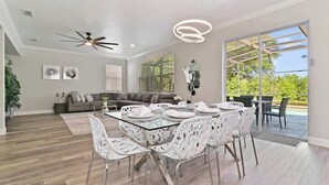 A spacious living area with a glass dining table, white chairs, a ceiling fan, and a view of the outdoors. - Stunning Private Villa with Pool and Spa (Davenport)