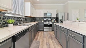 A modern kitchen with a dishwasher, stainless steel appliances, and a tiled backsplash. - Stunning Private Villa with Pool and Spa (Davenport)