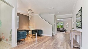 A spacious living area with a staircase, a chandelier, and a modern sofa. - Stunning Private Villa with Pool and Spa (Davenport)