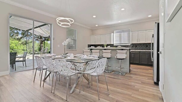 A modern kitchen with a dining area, large windows, and a view of greenery. - Stunning Private Villa with Pool and Spa (Davenport)