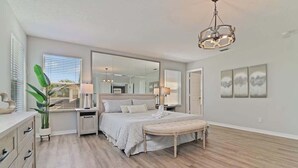 A bedroom with a bed, bedside tables, a mirror, a bench, and a chandelier. - Stunning Private Villa with Pool and Spa (Davenport)