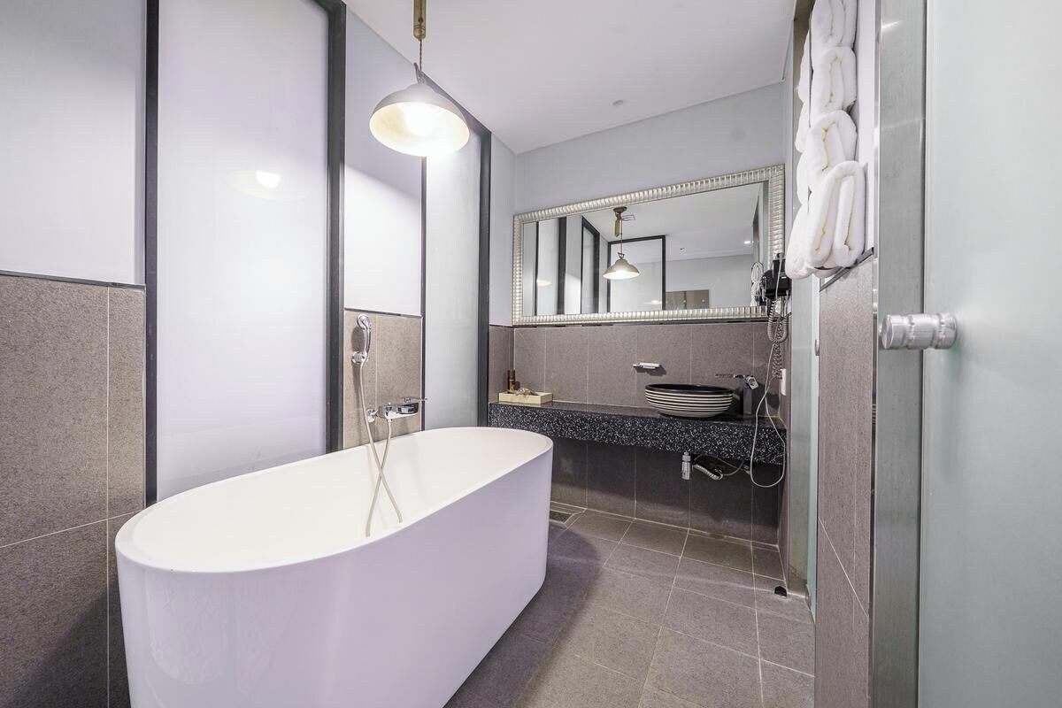 Un baño moderno con una bañera independiente, un espejo grande y una zona de ducha.