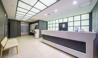 A reception desk with a glass partition, a bench, and a shelving unit with items.