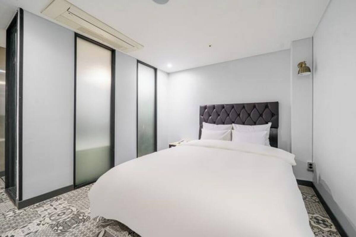 Una habitación de hotel con una cama grande, un puertas corredera y un cabecero moderno.