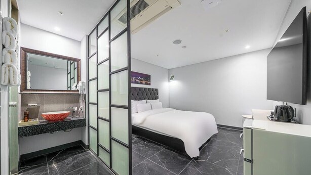 Habitació d'hotel moderna amb un llit, una menjadora amb mirall, un rentapins i un televisor de pantalla plana.