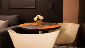 Una mesa redonda con un florero, dos individuales negros y una silla blanca.