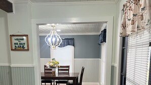 En matplats med ett träbord, stolar, en kristallkrona och en välkomnande skylt.