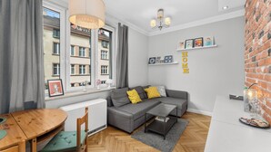 Un salon moderne avec un canapé gris, une table à manger en bois et un mur décoratif en briques.