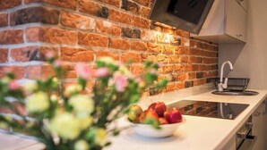 Une cuisine avec un mur en briques, un évier et un saladier rempli de fruits.