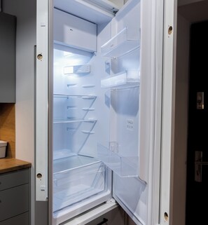 An open refrigerator with multiple shelves and a digital display. - Park Wilsona Charming Studio (Poznań)
