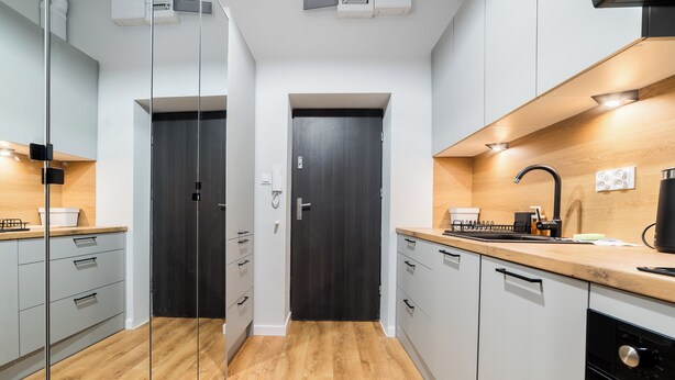 A modern kitchen with white cabinetry, a wooden countertop, a black faucet, and a built-in oven. - Park Wilsona Charming Studio (Poznań)