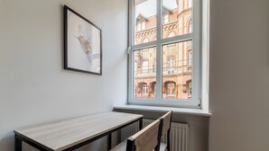 A corner room with a window, a framed picture, a table, and a chair. - Park Wilsona Charming Studio (Poznań)