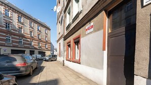 A street with parked cars, a building with a sign, and a clear sky. - Gliwice Comfort Stay Studio (Gliwice)