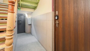 A hallway with a wooden door, a staircase, and a wall-mounted intercom. - Gliwice Comfort Stay Studio (Gliwice)