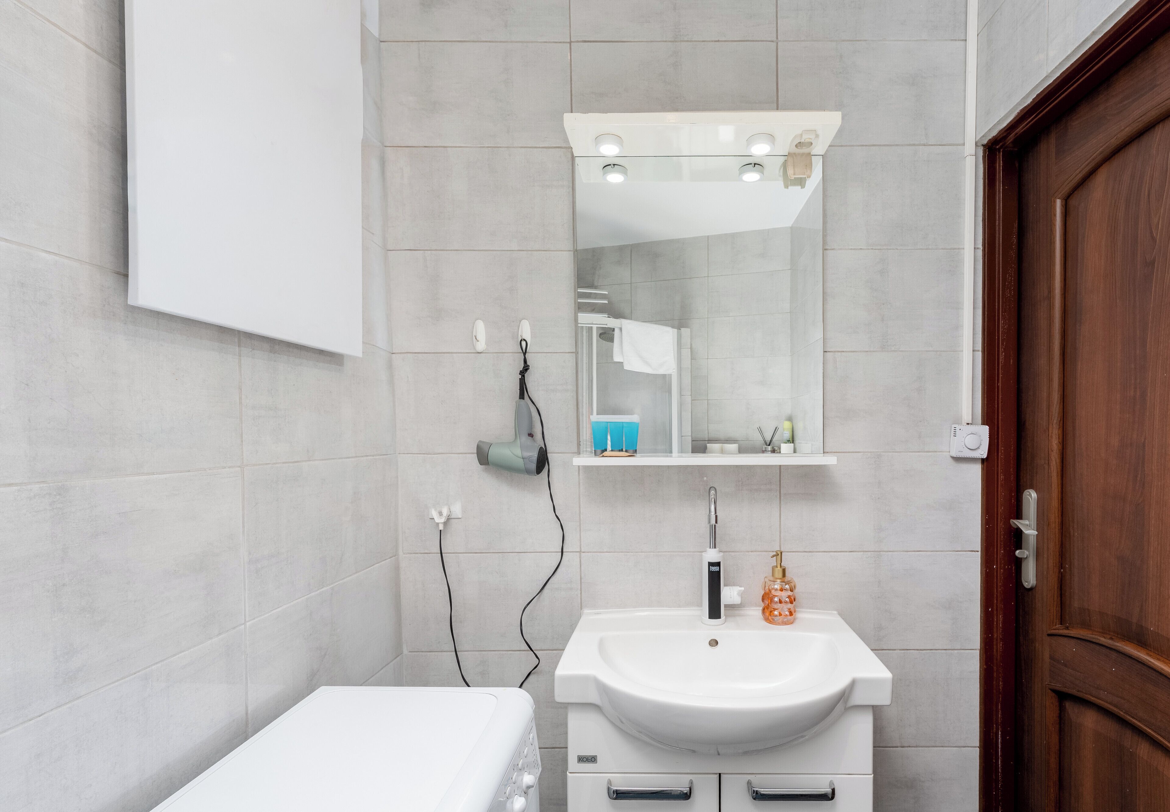 A bathroom with a white sink, mirror, and shower area.